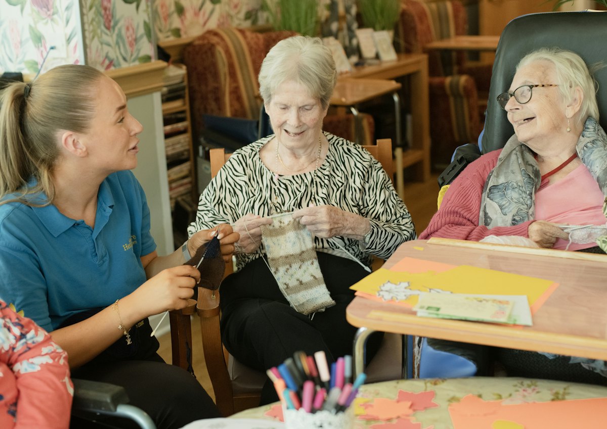 Een zorgverlener begeleidt twee bewoners tijdens een activiteit